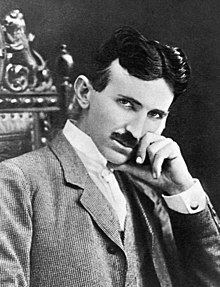 Photograph of Nikola Tesla, a slender, moustachioed man with a thin face and pointed chin.